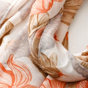 Macro view of linen-textured scarf showing orange floral patterns and breathable weave