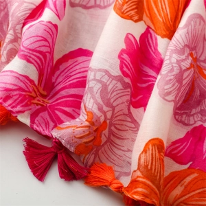 Close-up of lightweight floral scarf with soft pink and orange tassels and fabric texture