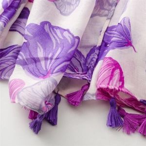 Detail of floral print on linen-feel scarf featuring purple flowers and fringe tassels