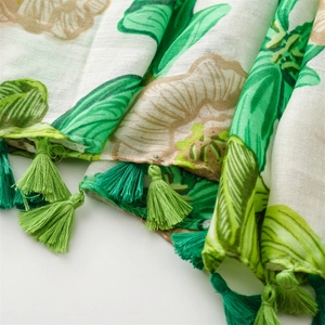 Detail of green floral linen scarf featuring artisanal tassels and woven texture
