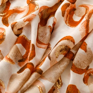 Detailed view of scarf fabric with gold foil donut patterns and fringed edges texture