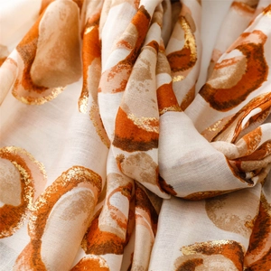 Detail of soft linen-feel scarf featuring gold foil donut patterns and frayed edges