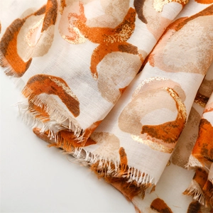 Detailed close-up of gold foil donut pattern on a white linen scarf with frayed edges