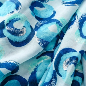Detailed close-up of blue swirl print with silver foil accents on cotton linen scarf