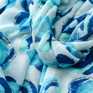Close-up of light blue scarf with blue dots and elegant silver metallic gold foil trim