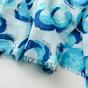 Detail of light blue scarf with silver glitter donuts and raw fringe edges
