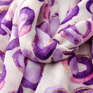 Detailed close-up of soft purple scarf featuring gold foil donut patterns and frayed edges