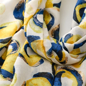 Close-up of cotton linen scarf featuring gold foil donut prints and raw fringe edges