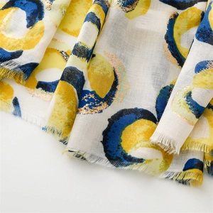 Detailed macro view of yellow and navy cotton linen scarf with gold foil donut patterns