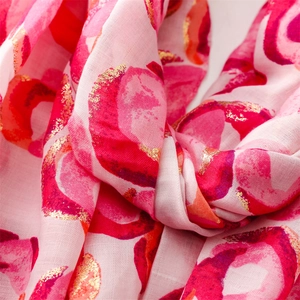 Macro view of soft pink cotton-linen shawl with golden donut foil print and raw edges