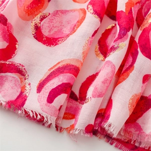 Macro detail of scarf showing gold foil donut print and soft cotton-linen texture