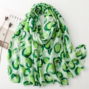Green linen-feel scarf with gold foil donut prints and frayed edges on white background