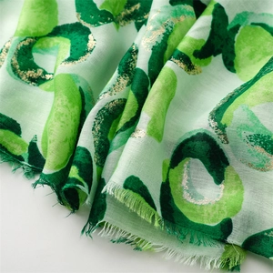 Detail of mint green scarf with dark leopard print, gold foil, and frayed edges texture