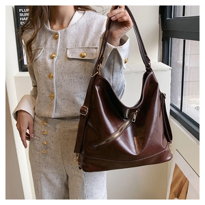 Detail of a deep brown faux leather tote with golden zipper on a tweed sleeve background