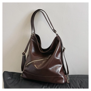 Vista de primer plano del bolso tote de cuero brillante marrón con cremalleras doradas