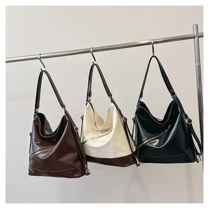 Tres bolsos tote grandes de cuero en marrón oscuro, crema y negro colgados en perchas