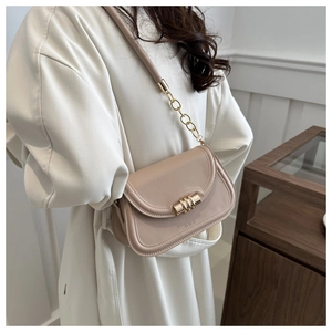 Detail view of apricot crossbody bag with gold hardware and chain strap on white coat