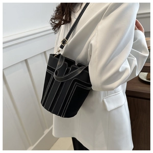 Secchiello in pelle nera con cuciture bianche a contrasto indossato da modella in tailleur