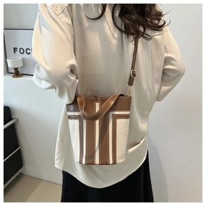 Dettaglio di una borsa a secchiello vintage in tela e pelle marrone con tracolla regolabile
