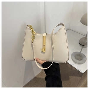 Detail of cream shoulder bag with gold textured chain and vintage metal buckle