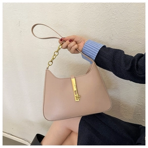 Close-up of minimalist beige PU leather crescent bag with gold chain and bar lock detail