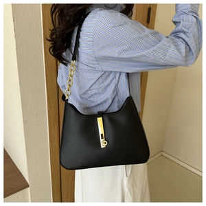 Detail view of black PU leather shoulder bag with golden bar lock and chain strap links