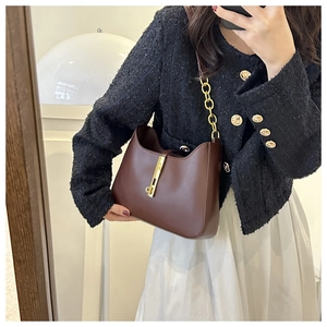 Détail du sac sous l'aisselle en cuir marron foncé avec fermoir doré sur veste en tweed