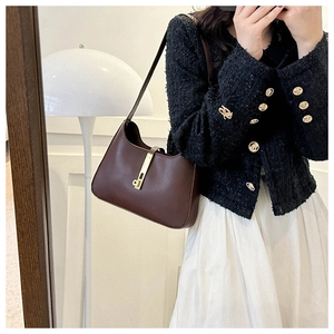 Detail view of deep brown leather hobo bag featuring a metallic piston closure on shoulder
