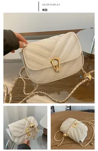 Détail du sac matelassé crème avec fermoir goutte doré et décorations de bandoulière