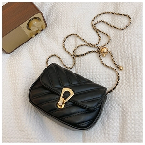 Detail of black quilted leather bag with golden chain strap and vintage clasp on white fabric