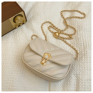 Detailed view of cream V-quilted faux leather bag with gold clasp and chain strap
