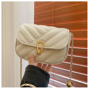 Detail of cream quilted bag with golden horseshoe lock and decorative chain ball