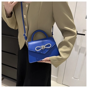 Close-up of the cobalt blue crossbody bag featuring a sparkling rhinestone bow buckle