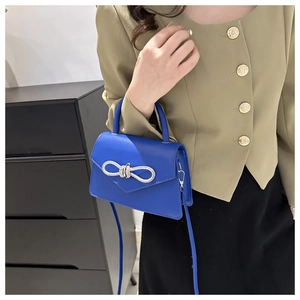 Detail van blauwe leren handtas met zilveren strikgesp op een kaki blazer outfit