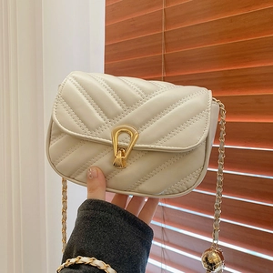 Chic cream quilted crossbody bag with gold lock and chain strap held by hand