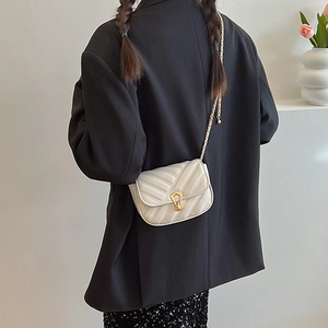 Chic chevron quilted cream crossbody bag with gold hardware shown on a model
