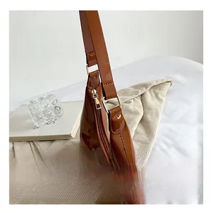 Close-up of glossy brown patent leather shoulder bag with gold metal hardware details