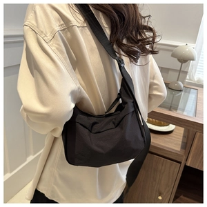 Minimalist black crescent crossbody bag shown on a model in a modern office setting