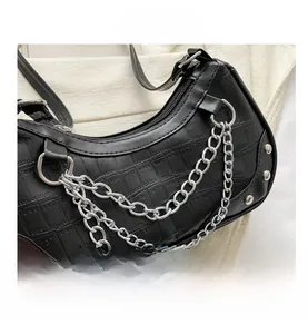 Detail of black faux crocodile skin underarm bag with silver chain and rivet accents