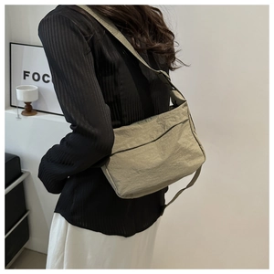 Detail of light green crossbody bag showing nylon crinkle texture and wide shoulder strap