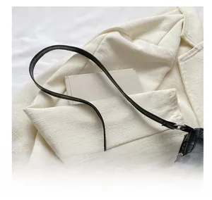 Detail of black faux crocodile leather shoulder bag with silver chain on tweed jacket