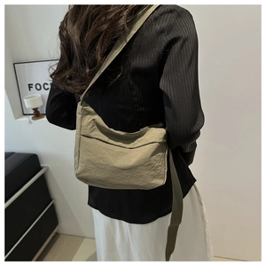 Close-up of olive green nylon crossbody bag with textured fabric on a model