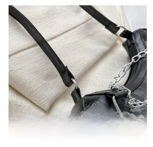 Detail of silver D-ring buckle and thick metal chain on black crocodile pattern bag