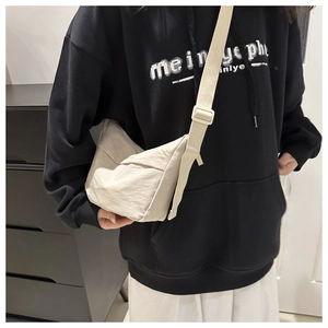 Detailed view of beige nylon crossbody bag texture with adjustable strap on model