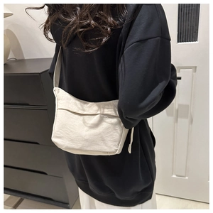 Model wearing a minimalist cream nylon tote bag over a black hoodie, back view shot
