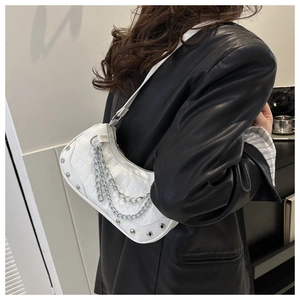 White croc-effect hobo bag with silver chain and metal studs worn by model in black leather jacket