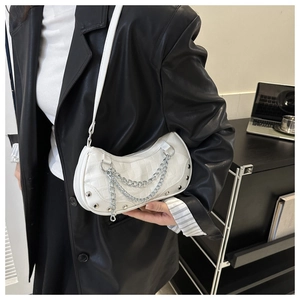 Close-up of white crocodile pattern underarm bag with silver chain and rivet details