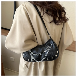 Detail of black crocodile texture shoulder bag with silver rivet chain on model