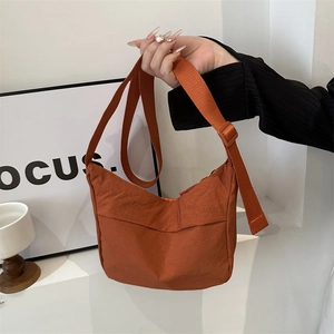 Burnt orange nylon half-moon crossbody bag with adjustable strap and minimalist design