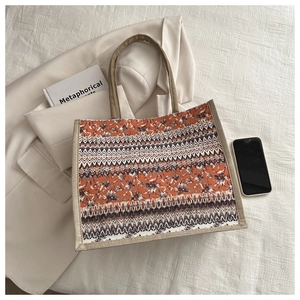 Detail of bohemian linen tote bag with geometric prints and jute handle on beige background